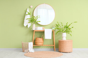 Interior of bathroom with blossoming branches in vases, mirror and baskets