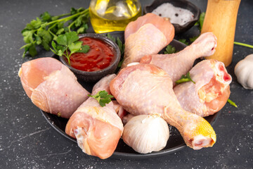 Chicken meat preparation background, raw chicken legs ready for grilling, with spices, salt, pepper, olive oil, garlic and marinade or sauce. Grilll and bbq season cooking background, copy space