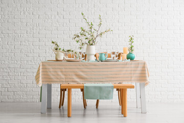 Elegant table setting with plates, glasses and blooming tree branches