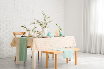 Elegant table setting with plates, glasses and blooming tree branches