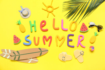 Composition with text HELLO SUMMER, mini beach accessories and palm leaf on yellow background