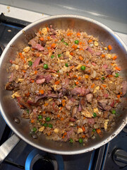 A pan of duck fried rice with vegetables.