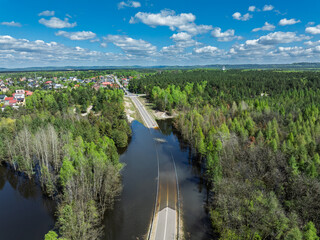 Lake District swallow hole flooded as a result of the mining damage Pomorzany mine in Olkusz,Poland. Aerial drone view of flooded road. Forest submerged in a lake. Sunken sandpit with clear water