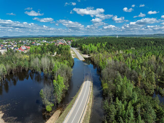 Fototapeta premium Lake District swallow hole flooded as a result of the mining damage Pomorzany mine in Olkusz,Poland. Aerial drone view of flooded road. Forest submerged in a lake. Sunken sandpit with clear water