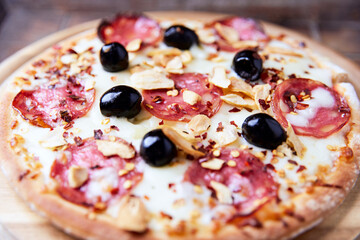 Pizza with salami and mozzarella cheese. Wooden background. Soft focus. Close up.