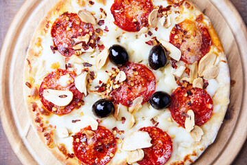 Pizza with salami and mozzarella cheese. Wooden background. Soft focus. Close up.	