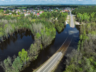 Obraz premium Lake District swallow hole flooded as a result of the mining damage Pomorzany mine in Olkusz,Poland. Aerial drone view of flooded road. Forest submerged in a lake. Sunken sandpit with clear water