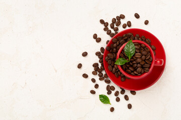 Roasted coffee beans with leaves on concrete background,top view