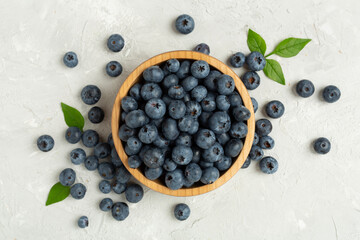 Bowl with fresh bright blueberries on concrete background,top view
