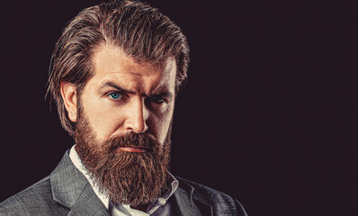 Portrait of a young handsome bearded man looking ahead. Perfect beard. Perfect beard. Close-up of young bearded man standing against black background