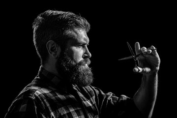 Barber hold with scissors. Barber scissors. Male in barbershop, haircut, shaving. Bearded man isolated on black background. Mans haircut in barber shop. Black and white