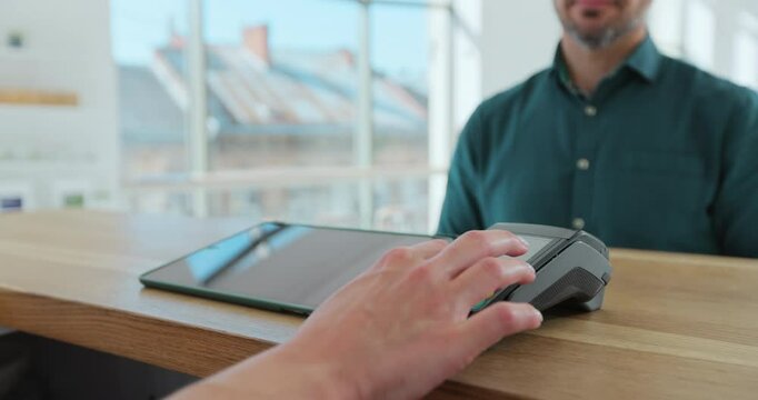 Man hand with smartwatch using terminal for payment in coffee shop, non-cash transaction, side view. Non-cash payment concept. Pos-terminal on table on black background.