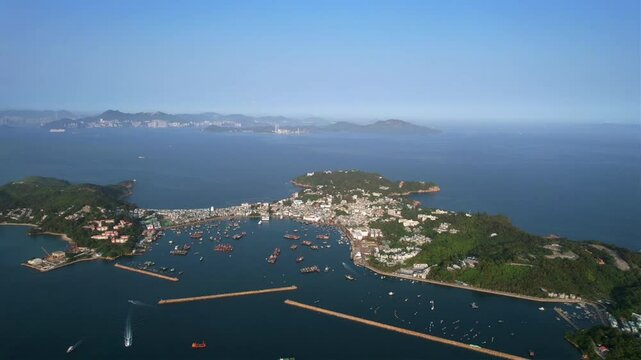 The island of Cheung Chau with greenery, boats and buildings surrounded by calm water