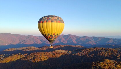Colorful hot air balloons float high above the beautiful autumn mountain scenery, the warm light of the rising sun casting long shadows
