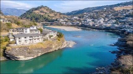 Obraz premium Aerial view of turquoise river with stone village and boat on rocky outcrop