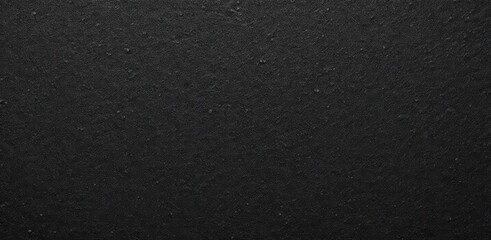 Close-up texture of a dark asphalt surface, showcasing its rough and grainy appearance commonly found on roads and pavements.