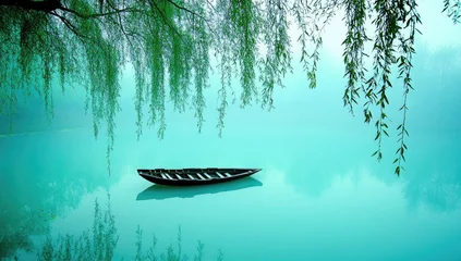 Fototapeten Tranquil lake scene with a lone boat and misty willows © Abdi
