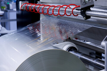 plastic packaging film on the automatic packing machine in food product factory. industrial and...