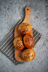 Yeast dough pies with sesame seeds on a wooden board