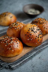 Yeast dough pies with sesame seeds on a wooden board