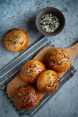 Yeast dough pies with sesame seeds on a wooden board