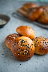 Yeast dough pies with sesame seeds on a wooden board