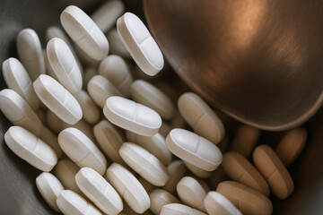 Pharma production line with white pharmaceutical tablets falling into container representing medicine manufacturing process in clean environment