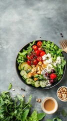A delicious and colorful salad with fresh vegetables, cheese, and dressing is presented on a grey textured surface in a dark bowl.