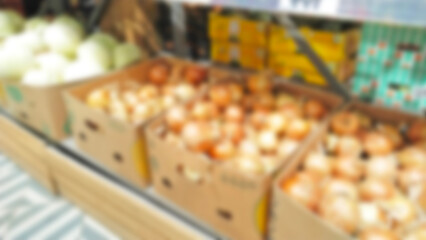 Blur image of vegetables, onion on supermarket defocused shelves. Retail industry. Local Farmers market. Grocery store. product. Food. Greengrocers stall. Veg. Family shop. Inflation. Rise price.