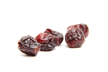 Close-up image of dried cranberries placed on a clean white surface, showcasing their wrinkled texture and dark red, glossy skin