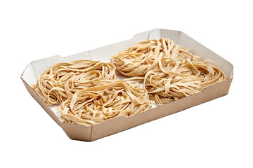 Bundles of uncooked whole grain tagliatelle pasta neatly arranged in a brown cardboard tray,...