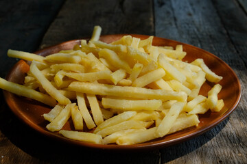 French fries in plate on wooden table.