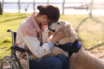 Woman in wheelchair hugging her service dog at park