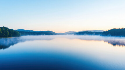 Fototapeta premium Serene lake surface reflects early morning mist and soft light, creating tranquil atmosphere