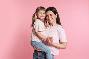 Happy mother and her cute daughter on pink background