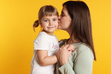 Happy mother and her cute daughter on orange background