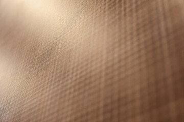 Blurred, close-up abstract image showcasing a checkered wooden brown surface. The play of light...