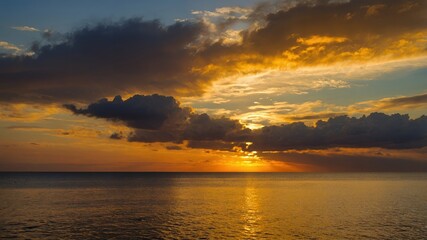 Obraz premium Dramatic Golden Sunset over Calm Ocean with Dark Cloudscape