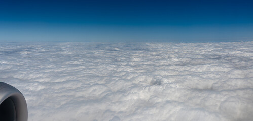 View from a plane window looking down on thick clouds with a blue color cast
