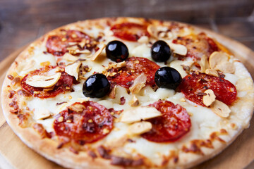 Pizza with salami and mozzarella cheese. Wooden background. Soft focus. Close up.	