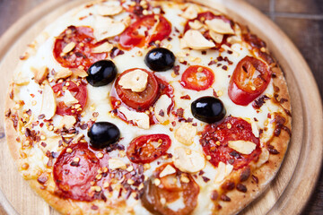 Pizza with salami and mozzarella cheese, jalapeno pepper and black olives. Wooden background. Soft focus.	
