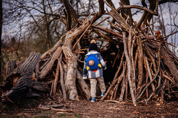 Child Exploring Wooden Stick Fort in Forest