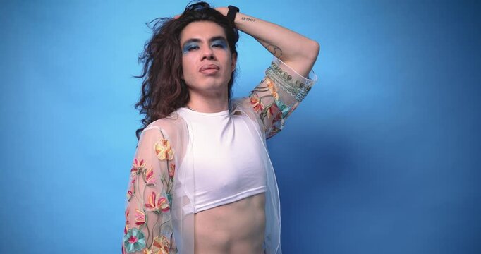 Happy and radiant non-binary stylish person with very long hair on blue background and copy space