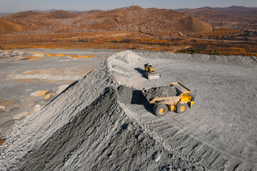 Open pit mine industry, big yellow mining truck for iron and gold ore, top view aerial banner