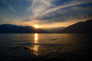 Sunset over an Alpine Lake Maggiore with Mountain and Orange clouds in Locarno, Ticino, Switzerland.