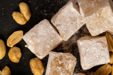 Turkish delight with nuts , scattered oriental sweets Turkish delight with peanuts on a slate board, top view
