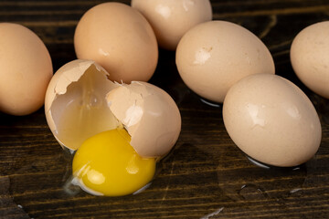 a chicken egg smashed on a black table, a broken cracked chicken egg spreads on a black wooden board