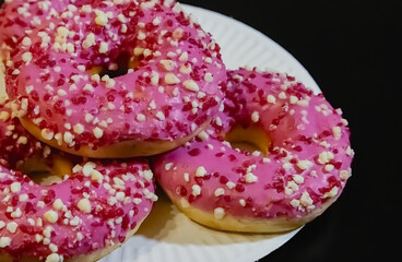 Chocolate doughnuts with chocolate glaze in a transparent plastic container on a black background