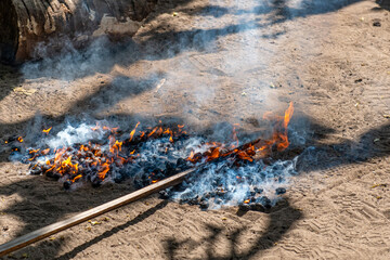dogasające płomienie podczas procesu wypalania toksycznego oleju z orzechów nerkowca, leżące n piasku gotówce orzechy muszą ostygnąć przed ich rozłupaniem © Kamil_k2p