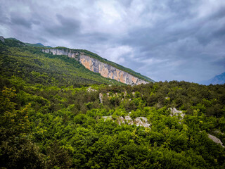 Obraz premium View From The Nago Climbing Base Camp In Italy, Overlooking Lush Green Forests And Rocky Cliffs
